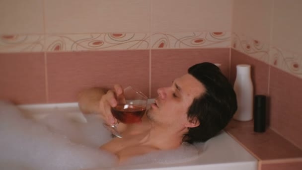 Чоловік приймає ванну і п'є коньяк і плаче. Депресія і проблеми в житті. Обличчя крупним планом . — стокове відео