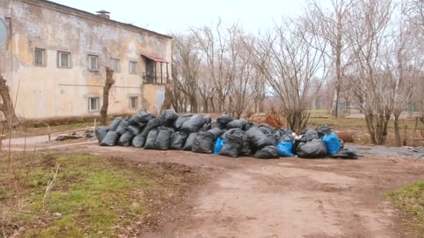 Bolsas de basura negras amontonadas en la ciudad contra la casa . — Vídeos de Stock