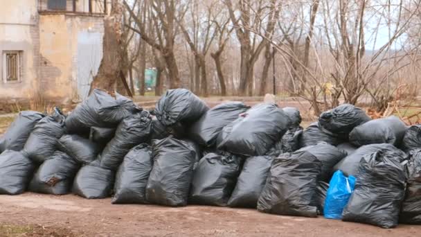 Крупный план черных мусорных мешков, нагроможденных в городе против дома . — стоковое видео