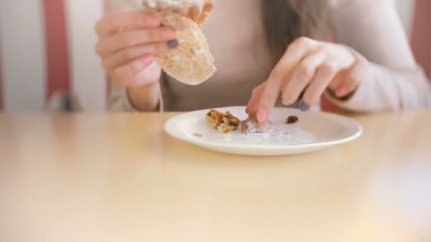 Vrouw eten een muffin met rozijnen. Close-up van een dames handen. — Stockvideo