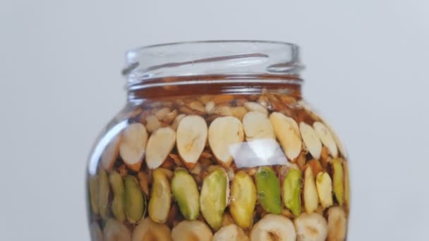 Rotující otevřené nádobky s ořechy v medu. Detail boční pohled. — Stock video