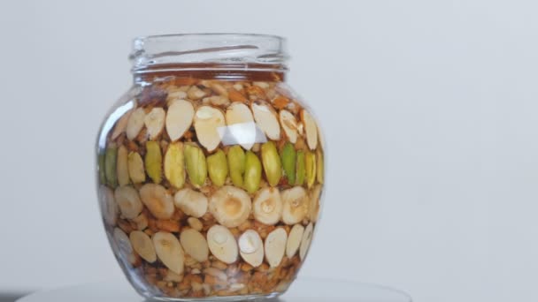 Rotierendes offenes Glas mit Nüssen in Honig. Seitenansicht aus nächster Nähe — Stockvideo