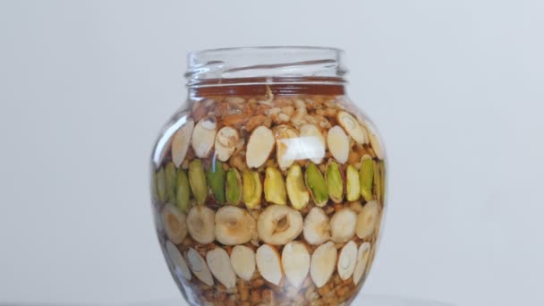 Open jar with nuts in honey. Close-up side view — Stock Video