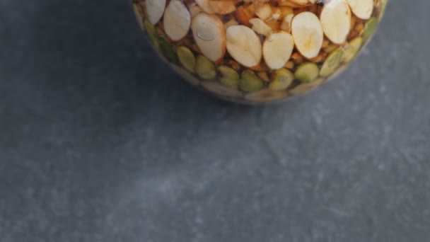 Part of jar with nuts in honey on black table. — Stock Video