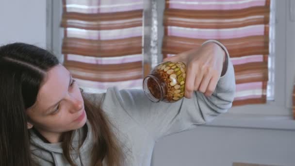 Mujer comiendo miel de un frasco de nueces en miel con el dedo . — Vídeos de Stock