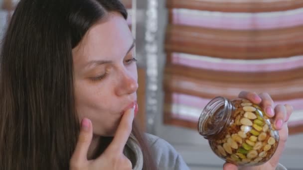손가락으로 벌 꿀에 견과류의 항아리에서 꿀을 먹는 여자. — 비디오