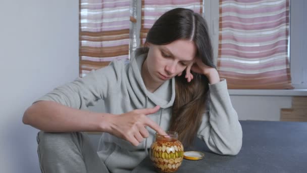 Γυναίκα βουτάει το δάχτυλό της στο μέλι με καρύδια στο βάζο. Τρώει μέλι από το δάχτυλό. — Αρχείο Βίντεο