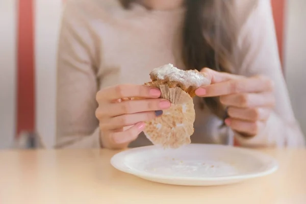 Женщина ест кекс с изюмом. Крупный план женских рук . — стоковое фото