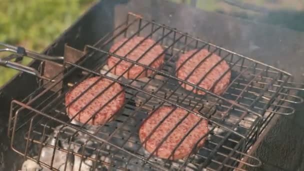 Rundvlees schnitzels op de grill. Close-up mans handen zet brood op grill. — Stockvideo