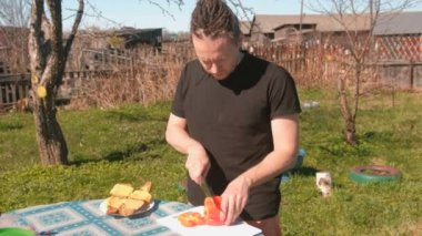 Genç adam kırmızı biber tahtada keser. Sandviç hazırlanması.