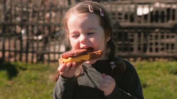 Jeune jolie petite fille mange un sandwich avec escalope et fromage . — Video