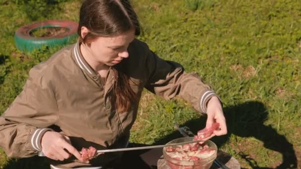 La joven pone la carne en un pincho. Cocinar kebabs de cerdo . — Vídeos de Stock