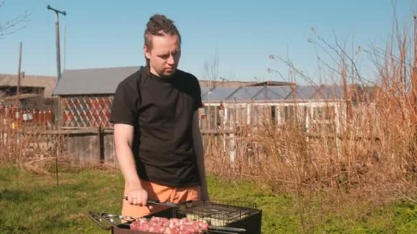 Человек жарит мясо барбекю свинина и цуккини на гриле . — стоковое видео