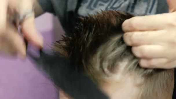 Closeup barbers hands combs and cutting blond short boys hair with scissors. Front view. — Stock Video