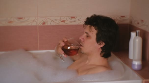 O homem toma banho com espuma e bebe conhaque. Depressão e problemas na vida . — Vídeo de Stock