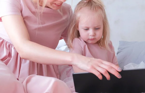 Encantadora niña rubia viendo un video en la tableta con su mamá . — Foto de Stock