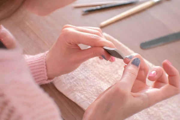 Kvinna filspån naglar nagelfil. Närbild händer. Verktyg på bordet. — Stockfoto