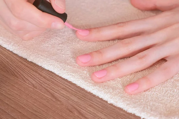Femeia pune primul strat de șelac roz pe unghii. Mâini de aproape — Fotografie, imagine de stoc