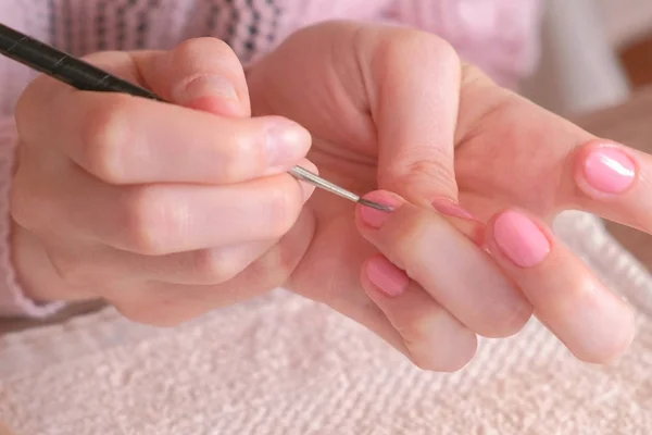 Mulher coloca primeira camada de goma-laca rosa em suas unhas com borla pequena. Mãos fechadas . — Fotografia de Stock