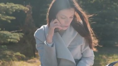 Çimenlerin üzerinde bahar parkta oturan ve bir cep telefonu üzerinde konuşurken öğrenci kadın portresi.
