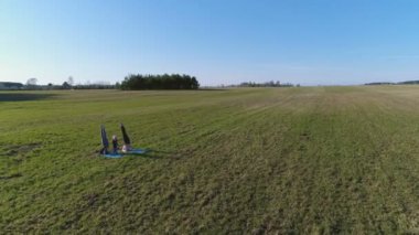 Parkta çim paspas oturan kızlar. Uçuş alanının üstündeki.