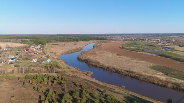 Vuelo sobre campos verdes, bosque, río y pueblo a principios de primavera, vista panorámica aérea . — Vídeos de Stock