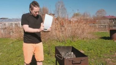 Genç adam bir kesme tahtası ile ızgara mangal kömürleri açılırsa.