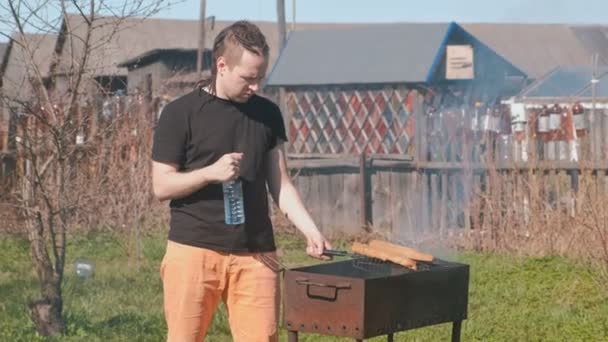 Νεαρός άνδρας ψήσιμο μοσχάρι κοτολέτες με ψωμί στη σχάρα. — Αρχείο Βίντεο
