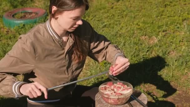 Νεαρή γυναίκα βάζει το κρέας σε σουβλάκι. Μαγειρική κεμπάμπ χοιρινό. — Αρχείο Βίντεο