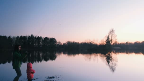 Μαμά και κόρη στη λίμνη για ψάρεμα κατά το ηλιοβασίλεμα το βράδυ. — Αρχείο Βίντεο