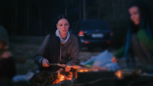 Zwei Frauen braten Würstchen auf einem Feuer. Familiencamping in der Nacht. — Stockvideo