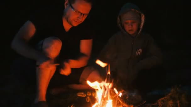 Hijo y padre encienden un fuego en el bosque. Camping familiar . — Vídeo de stock
