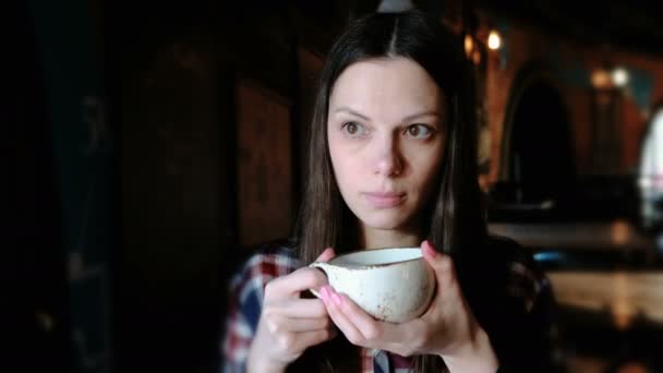 Mujer morena con camisa a cuadros bebiendo té de una taza grande. Mujer cansada tomar un té . — Vídeos de Stock