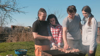 Grup Genç insanlar arkadaşlar Barbekü şaşlık et arka bahçesinde üzerinde kömür ızgara üzerine. Konuşmak ve birlikte gülümseyen.