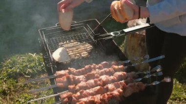 Kadın ızgara raf ile soğan ekmek koyar. Domuz Barbekü üstünde tepe-in kömür ızgara şiş üzerinde kavrulmuş. Yakın çekim kadının elleri.