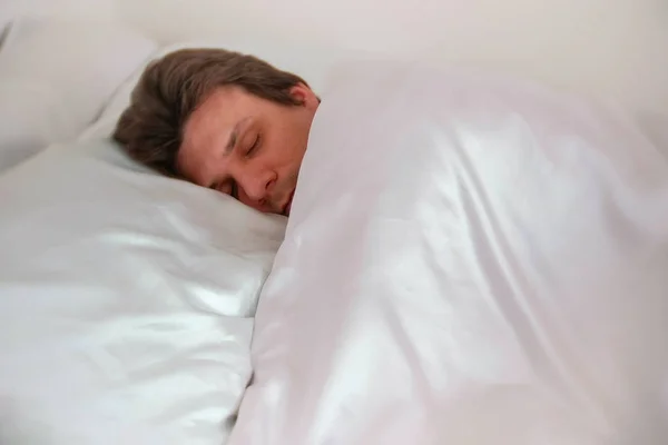 El hombre está durmiendo en la cama solo debajo de la manta. Vista lateral . —  Fotos de Stock