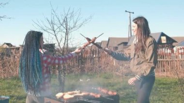 İki kadın arkadaş üstünde tepe-in arka bahçesinde üzerinde kömür ızgara Kebab et pişirmek. Konuşmak ve birlikte gülümseyen, hafta sonu dinlen.