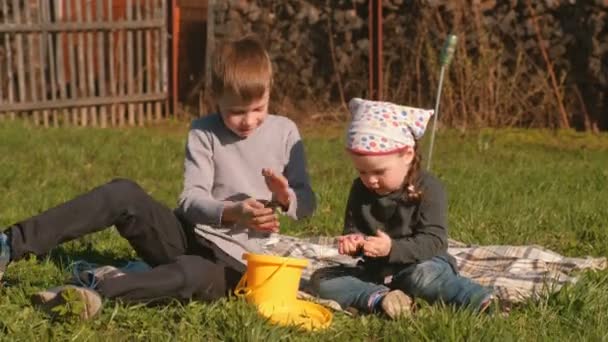 Bratr a sestra žížaly pohled sedí na trávníku v zahradě domu. — Stock video