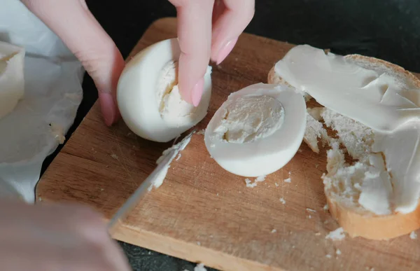 Крупным планом женские руки режут яйцо. Делаю сэндвич . — стоковое фото