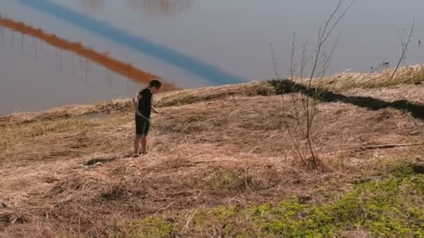 Man vangt slangen in de droog gras op de rivieroever. — Stockvideo