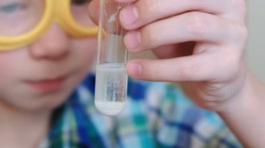 Evde kimya üzerinde deneyler. Sürpriz bir çocuk elinde bir tüp gaz kimyasal reaksiyon ile belgili tanımlık serbest bırakmak. Portre.