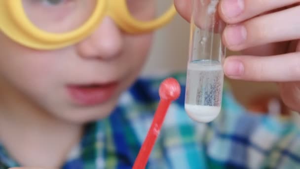 Experiment på kemi hemma. Kemisk reaktion med lanseringen av gas i ett provrör i händerna på en förvånad pojke. Närbild. — Stockvideo
