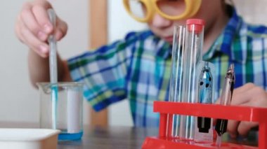 Evde kimya üzerinde deneyler. Oğlan mavi sıvı kabı bir pipet ile test tüp içine dökülen.