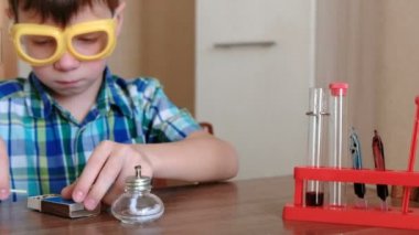 Evde kimya üzerinde deneyler. Çocuk tüp üzerinde alkol lamba yanan kırmızı sıvı ile ısıtır.