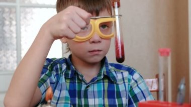 Evde kimya üzerinde deneyler. Çocuk test tüpü içeriğini denetler.