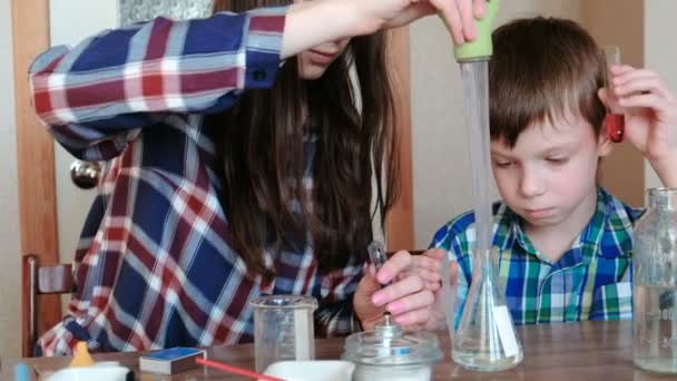 Chemie-Experimente zu Hause. Mama gießt mit einer großen Pipette Wasser aus der Flasche in den Kolben. — Stockvideo