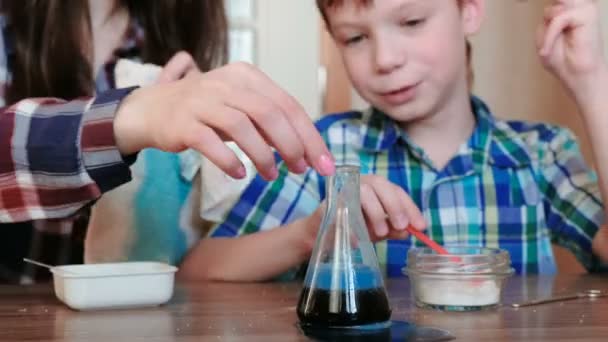 Chemistry experiments at home. Mom and son make a chemical reaction with the release of gas in the flask. — Stock Video