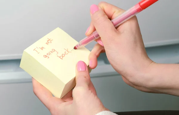 Крупным планом женщины руки писать на желтой наклейке бумажных листов слова им не собирается . — стоковое фото