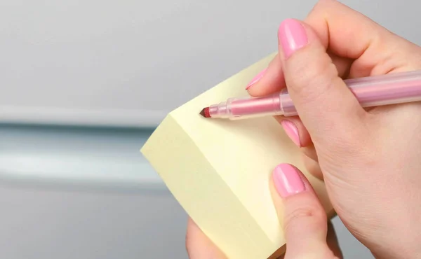 Крупный план женские руки пишет что-то на желтых листах бумаги наклейки . — стоковое фото