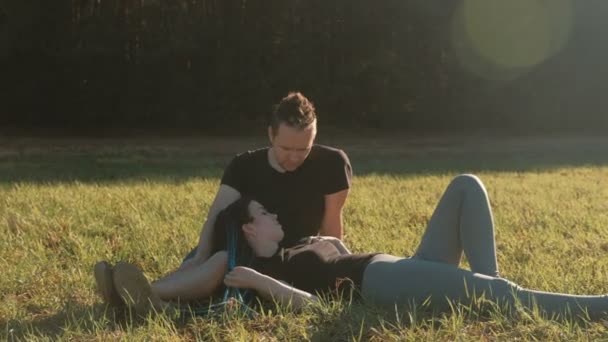 Par älskare koppla av i park ligger på gräset och chatt. — Stockvideo